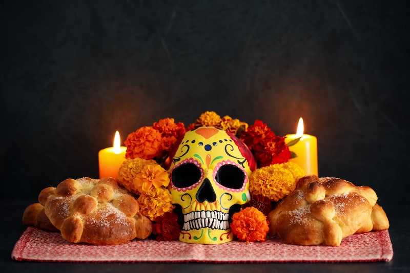 A traditional Día de los Muertos ofrenda with Day of the Dead food, marigolds, and candles displayed.