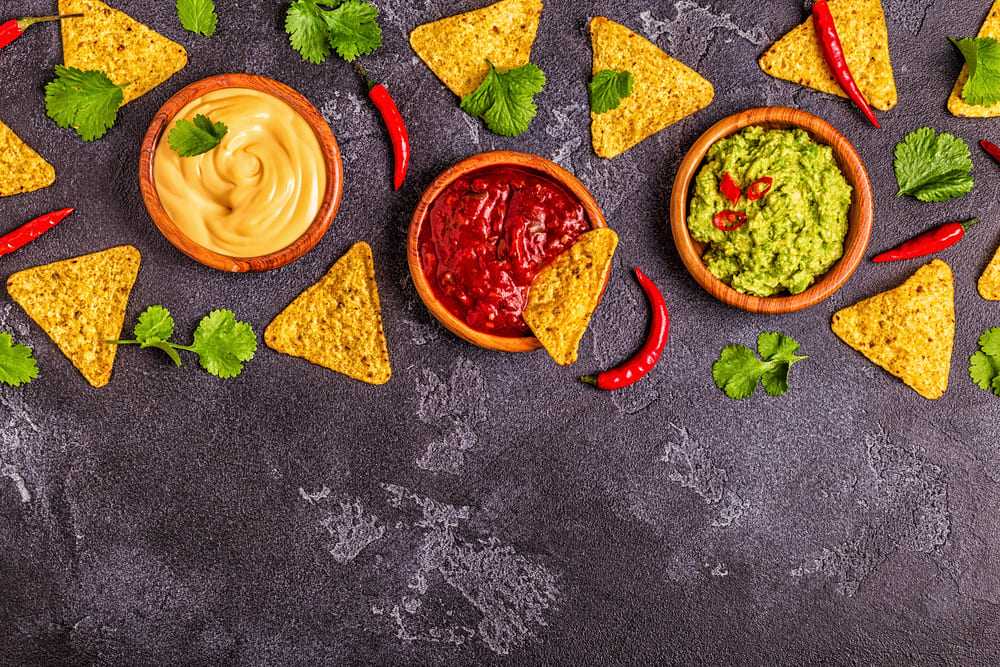 Cheese dip, salsa, and guacamole with ingredients scattered around at one of the restaurants in Chattanooga TN.